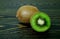 Half bright juicy ripe beautiful kiwi and whole kiwi on a coarse dark wooden background from boards