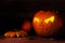 Half carved halloween pumpkin with glowing eyes on dark rustic w