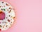 Half circle donut with white icing and choclate rainbow sprinkles on a trendy pink background. Tasty doughnutdonut, top