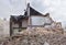 Half collapsed brick house covered in dust and debris