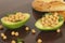 Half cut avocado with boiled chickpeas and parsley inside, vegan diet meal on wooden background.