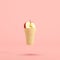 Half-cut red apple in ice-cream cone floating on pastel pink background