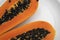 Half cut ripe papaya with seed on a white plate. Slices of sweet papaya with a white background. Halved papayas. Healthy