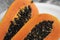 Half cut ripe papaya with seed on a white plate. Slices of sweet papaya with a white background. Halved papayas. Healthy