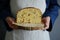 Half-cut sweet bread in the hands of a baker`s woman