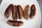 Half a dozen British pork sausages cooked and displayed on a white plate