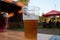 Half drunk mug of cold beer on wooden table with blurred pub garden in background