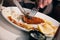 Half eaten fish and chips dish being cut using cutlery by a woma