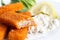 Half eaten fish fingers with lemon and tartar sauce