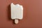 Half eaten milkshake flavor popsicle on a brown background with copy space