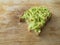 Half eaten slice of brown bread with guacamole topped lying on a wooden surface