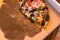 Half eaten vegetarian woodfire pizza in cardboard box on wooden table setting