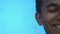 Half-face of cheerful black boy smiling at camera against blue background
