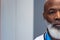 Half face portrait of african american senior male doctor in hospital corridor, copy space