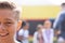 Half face portrait of smiling caucasian elementary schoolboy in school playground, copy space