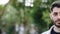 Half face of upset bearded caucasian young man looking straight to camera while standing outdoors in empty town. Half