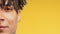 Half face of young african-american man with dreadlocks on yellow, copy space