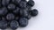 Half frame macro of fresh blueberries pile slowly rotates on a white background. Isolated. Macro.