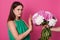 Half length of lady dressed green sundress, refuses beautiful bouquet of white and pink peony flowers from faceless person on