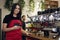 Half length millennial portrait of female barista enjoying job at coffee shop