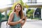 Half length portrait of cheerful Brazilian female on street using smartphone. Beautiful millennial girl looking at camera in the