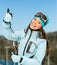 Half-length portrait of female downhill skier thumbing up