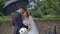 Half-length portrait of the happy gorgeous newlywed couple tenderly rubbing noses under umbrella in the rain.