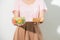 Half-length portrait of very beautiful woman holding small cake, fresh vegetables. Young housewife choosing sweets or healthy