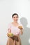 Half-length portrait of very beautiful woman holding small cake, fresh vegetables. Young housewife choosing sweets or healthy