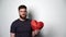 Half length portrait of young bearded hipster man holding red heart shape