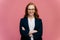 Half length shot of ginger business lady satisfied after conference, keeps arms folded, wears optical glasses, elegant black suit