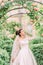 Half-length side portrait of the bride touching the roses on the arch.