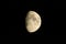 Half lit moon showing craters and surrounded by black sky taken from Radcliffe, England