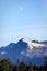 Half moon reveals itself over Alaskan mountaintops on summer evening