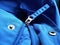 Half-open sewing lock on a blue synthetic fabric jacket. Open sewing buttons