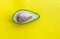 Half part of avocado on yellow background