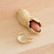 Half peeled peanut with cracked shell on a wooden table.