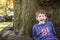 half portrait of laughing eight year old birthday boy sitting by a tree