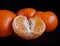 Half purified mandarine and whole tangerines. black background