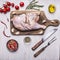 Half raw chicken,Ingredients for cooking, tomatoes, knife and fork for the meat, peppers wooden rustic background top view