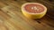 Half red grapefruit rotating on wooden table