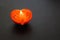 Half a red ripe heart shaped tomato on a black background