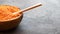 Half a round wooden bowl filled with red lentils with a wooden spoon. Dark background. Place for text