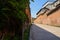 Half-shaded slopy road between old brick buildings in sunny summer afternoon