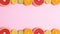 Half sliced citrus fruits appear on top and bottom on pastel pink background. Stop motion flat lay