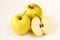 Half sliced and whole golden delicious apples on light beige background
