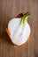 A half of a sprouting bulb or common onion and lying on a wooden cutting board. The layers of the vegetable are visible and also