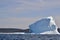 Half sunlit and shaded iceberg in bay outside St. John\\\'s with coastline on the horizon