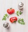 Half of tomatoes with herbs and salt and peppers on white wooden background, top view, simple food