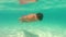 Half underwater, blurry turquoise ocean waves, slow motion close up video. Well trained boy in red trunks swim to sea. Thailand,